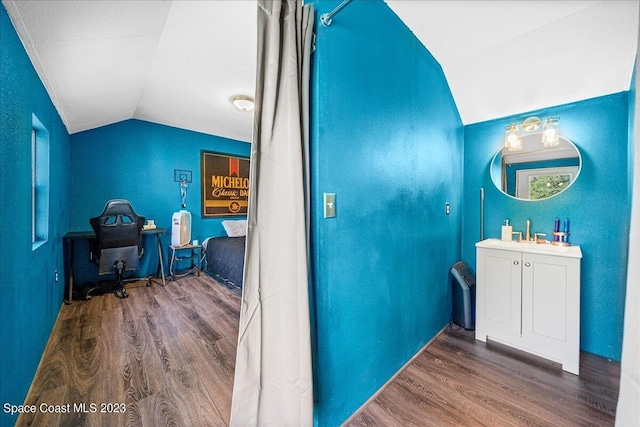 bathroom featuring vanity, vaulted ceiling, and wood-type flooring