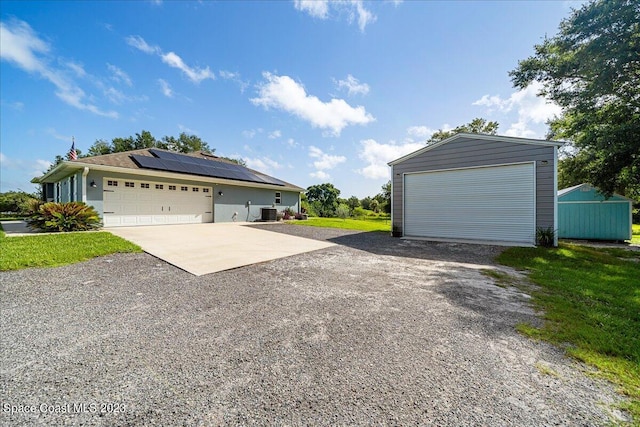 view of home's exterior featuring an outdoor structure, solar panels, a lawn, and a garage