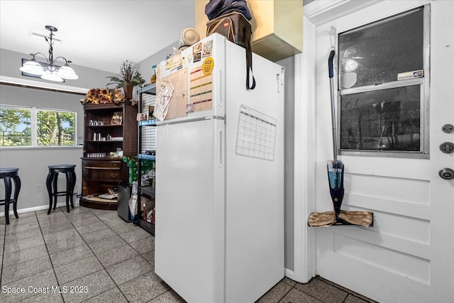 3706 Sutton Dr, Orlando, FL 32810 - kitchen featuring light tile floors, a chandelier, white fridge, and crown molding