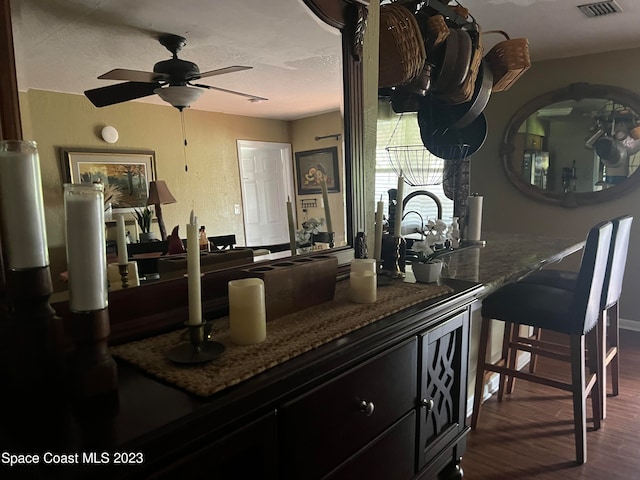 kitchen with dark stone counters, dark wood-type flooring, and ceiling fan