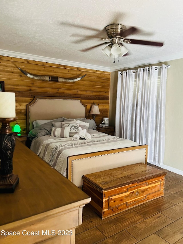 bedroom with crown molding, dark hardwood / wood-style flooring, ceiling fan, and wood walls