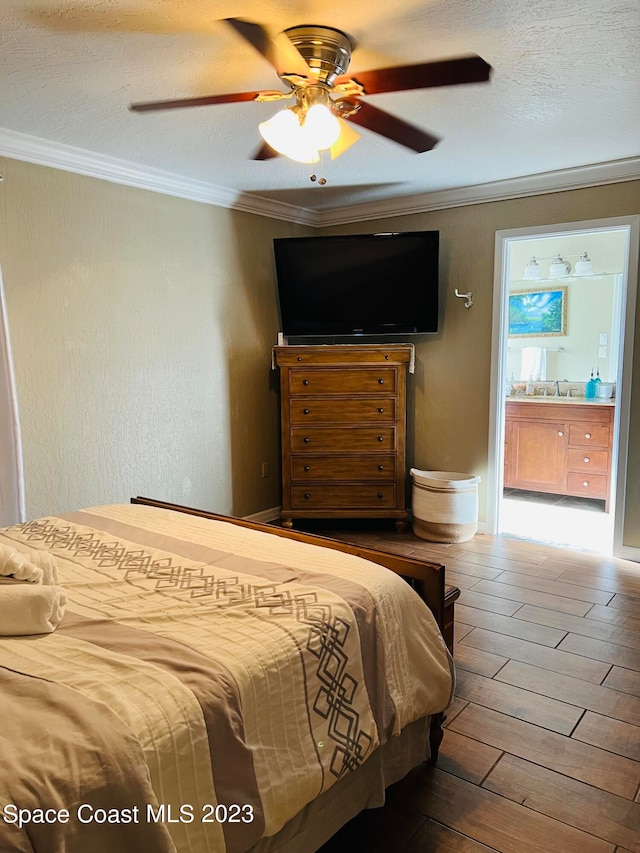 bedroom featuring ceiling fan, connected bathroom, wood-type flooring, a textured ceiling, and crown molding