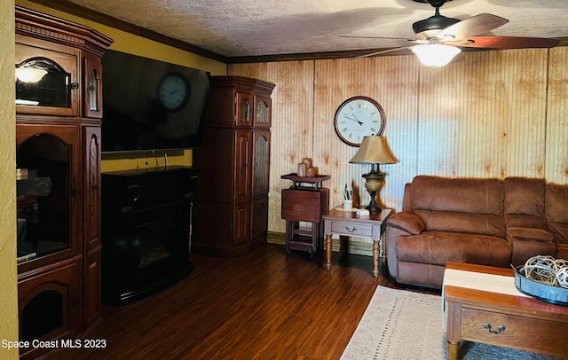 living room with dark hardwood / wood-style floors, ceiling fan, wood walls, a textured ceiling, and crown molding