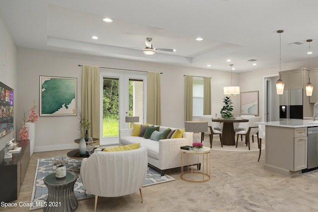 living room featuring a raised ceiling, ceiling fan, and sink