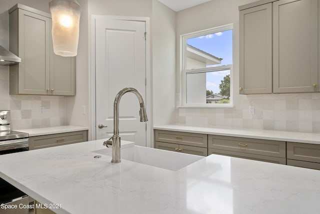 kitchen featuring backsplash, gray cabinets, sink, and light stone counters