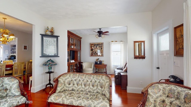 interior space featuring ceiling fan with notable chandelier, multiple windows, and dark wood-type flooring