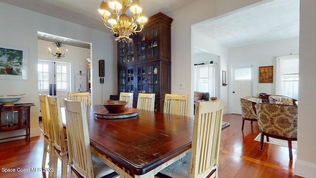 dining area with french doors, dark hardwood / wood-style floors, and an inviting chandelier