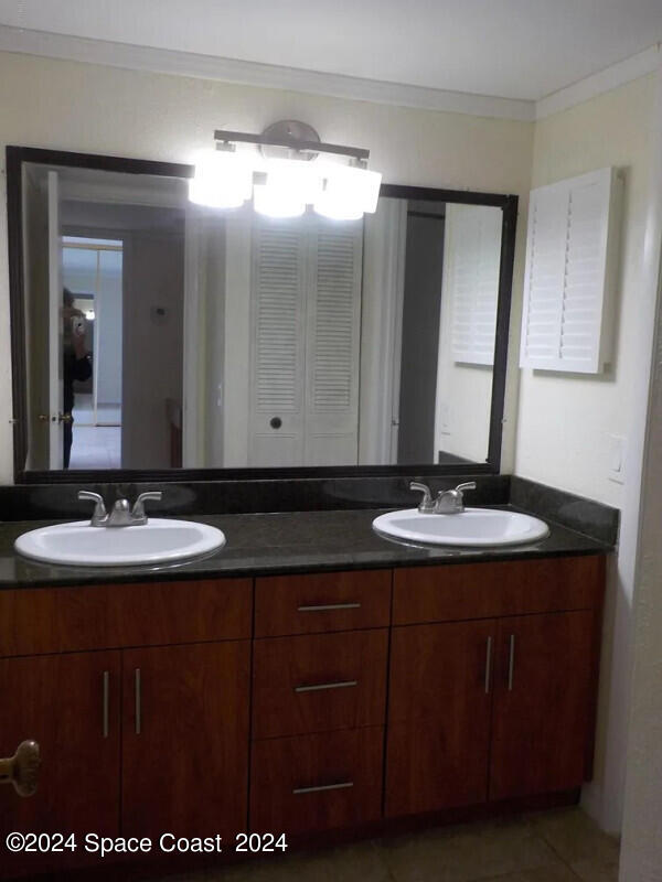 bathroom featuring tile patterned floors, crown molding, and vanity