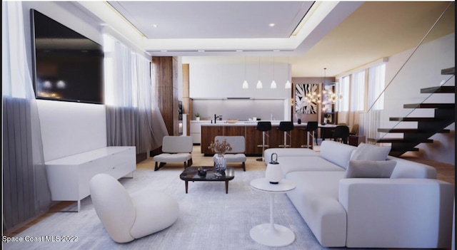 living room with a tray ceiling and a chandelier