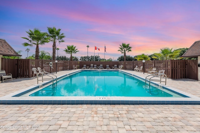 pool at dusk featuring a patio area