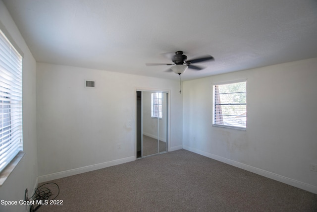 unfurnished room featuring ceiling fan and dark colored carpet