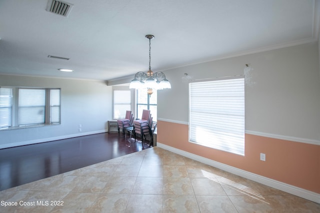 tiled spare room featuring crown molding and an inviting chandelier