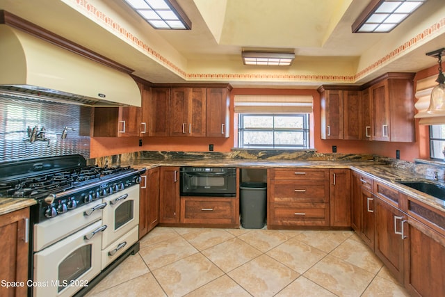 kitchen with black oven, pendant lighting, light tile floors, custom range hood, and range with two ovens