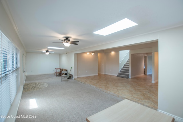 interior space with light tile floors, ornamental molding, ceiling fan, and a skylight