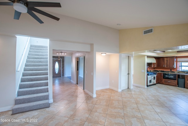 kitchen featuring ceiling fan, light tile floors, white range with gas cooktop, a high ceiling, and black microwave