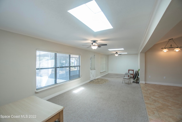 living room featuring light tile flooring, a skylight, ornamental molding, and ceiling fan