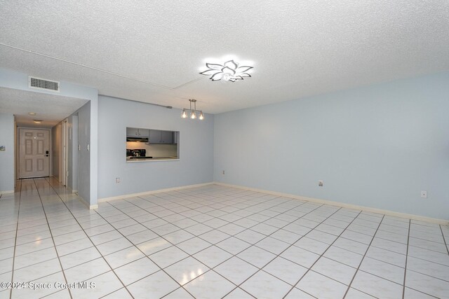 5800 N Banana River Blvd Unit 115, Cape Canaveral, FL 32920 - unfurnished living room featuring a textured ceiling, a chandelier, light tile patterned floors, and baseboards