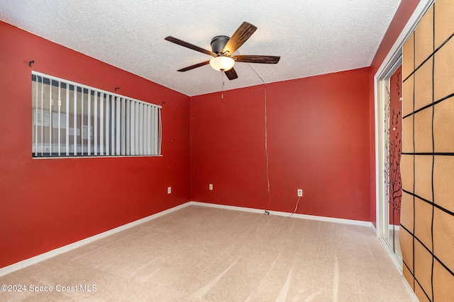 carpeted empty room with a textured ceiling and ceiling fan