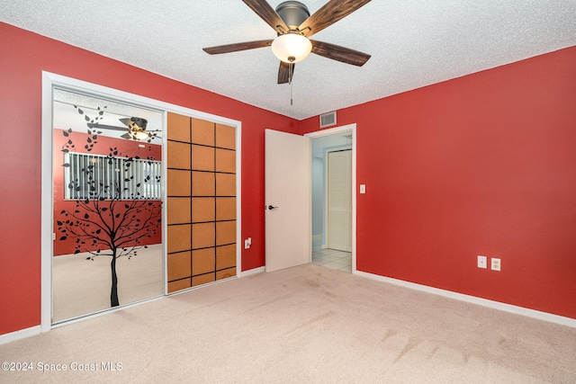 unfurnished bedroom featuring a textured ceiling, light carpet, ceiling fan, and a closet