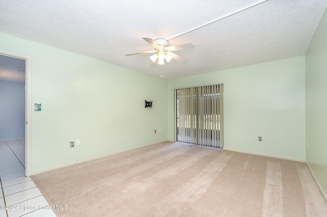 spare room with ceiling fan, a textured ceiling, and light carpet