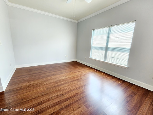 empty room with ceiling fan, ornamental molding, and dark wood-type flooring