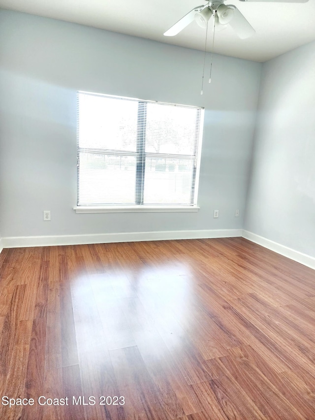 spare room featuring ceiling fan, dark wood-type flooring, and a wealth of natural light