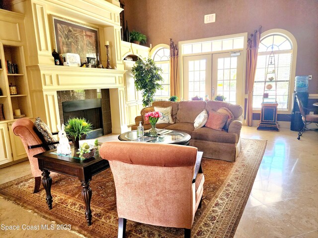 tiled living room featuring french doors, built in features, a towering ceiling, and a fireplace