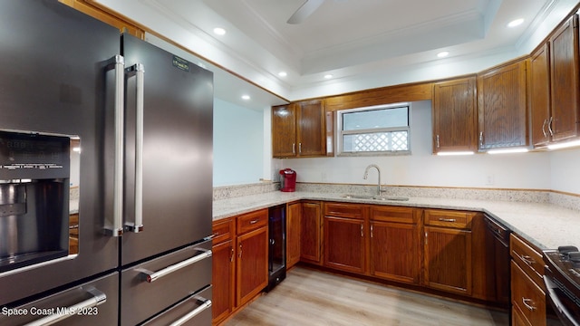 kitchen featuring a tray ceiling, ceiling fan, high end refrigerator, sink, and light wood-type flooring