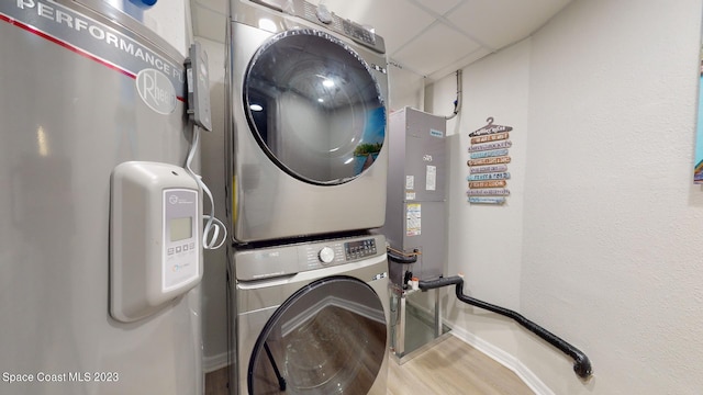 clothes washing area with hardwood / wood-style floors and stacked washer / dryer