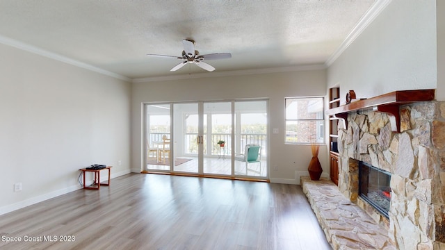 living room with ceiling fan, a fireplace, light wood-type flooring, a textured ceiling, and ornamental molding