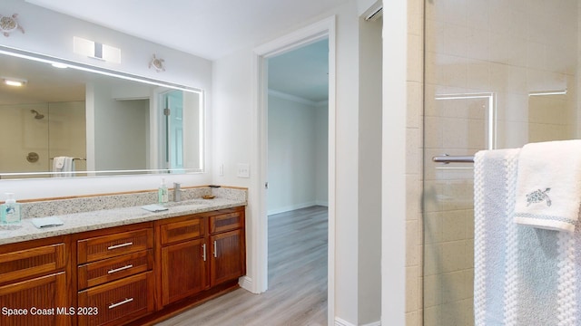 bathroom featuring vanity, walk in shower, hardwood / wood-style flooring, and ornamental molding