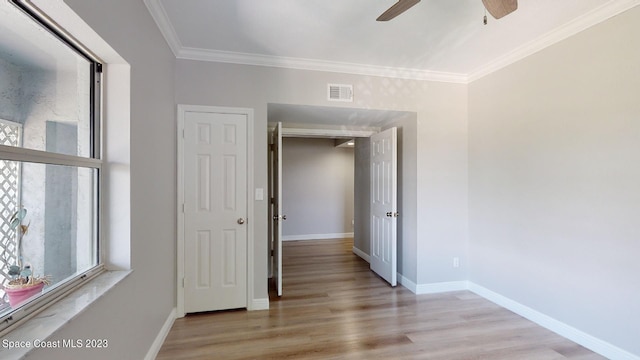 empty room with ceiling fan, light wood-type flooring, and crown molding