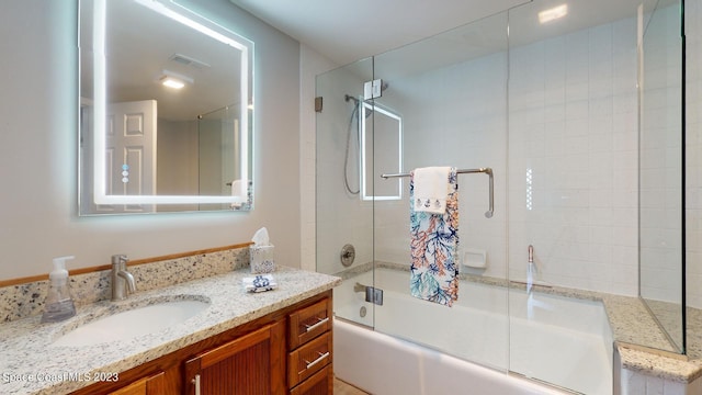 bathroom featuring combined bath / shower with glass door and vanity