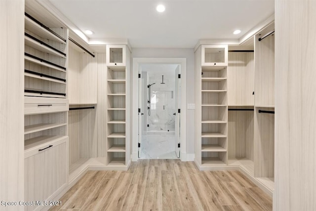 walk in closet with a barn door and light hardwood / wood-style floors