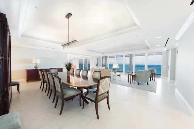 dining space with a water view, a wall of windows, and a tray ceiling