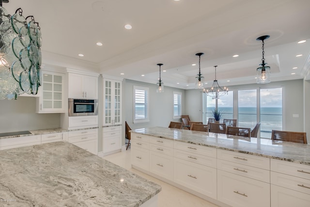 kitchen featuring oven, white cabinets, a chandelier, a water view, and decorative light fixtures