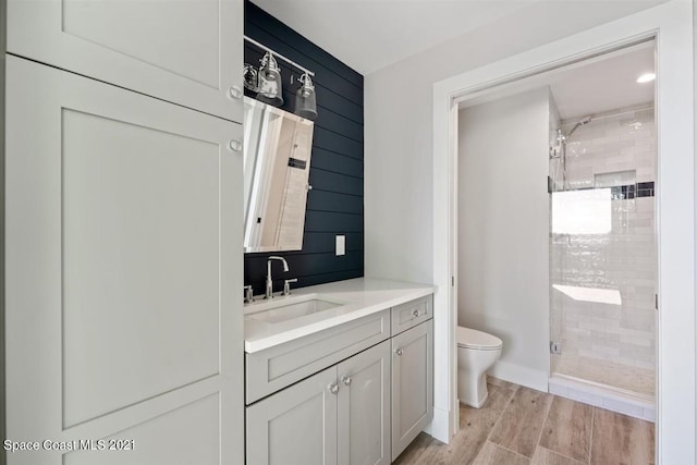 bathroom featuring vanity, a tile shower, wood-type flooring, and toilet