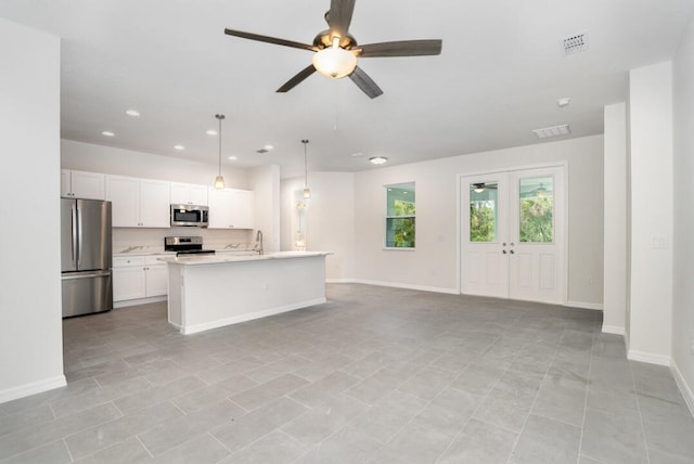 kitchen with stainless steel appliances, hanging light fixtures, an island with sink, and light tile floors