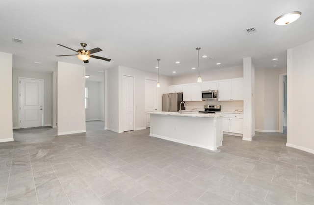 kitchen with decorative light fixtures, stainless steel appliances, a center island with sink, ceiling fan, and white cabinets