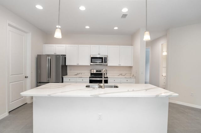 kitchen with light tile floors, pendant lighting, a center island with sink, and stainless steel appliances