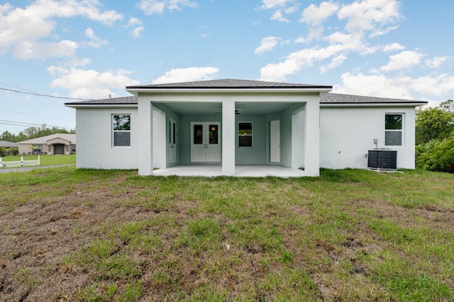 rear view of property with a patio, central air condition unit, and a yard