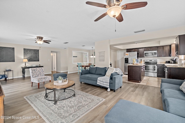 living room with sink, ceiling fan, and light hardwood / wood-style flooring