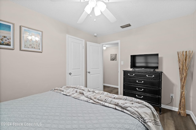 bedroom featuring dark hardwood / wood-style flooring, a textured ceiling, and ceiling fan