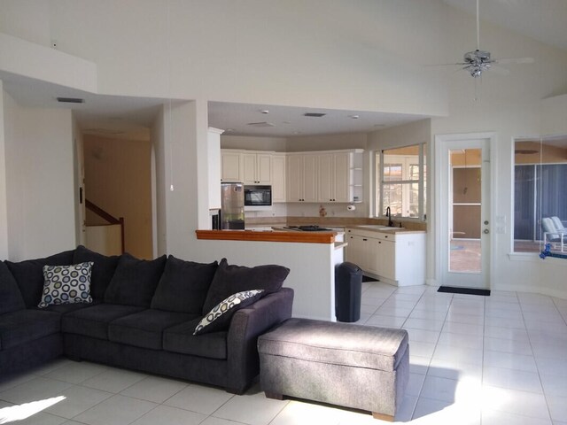 living room with high vaulted ceiling, sink, ceiling fan, and light tile patterned floors