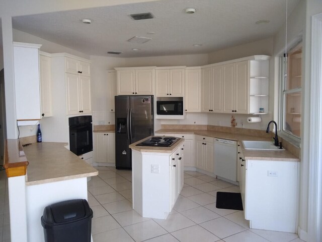 kitchen featuring white cabinetry, light tile patterned floors, a kitchen island, black appliances, and sink