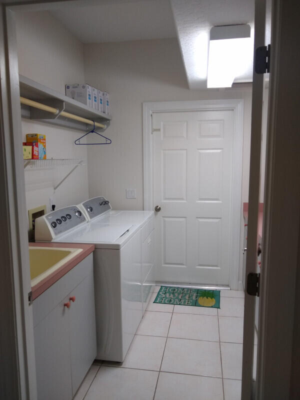 washroom featuring sink, washing machine and dryer, cabinets, and light tile patterned floors