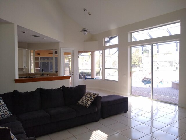 tiled living room with sink, ceiling fan, and a high ceiling