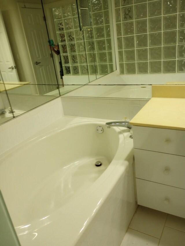 bathroom with tiled tub, vanity, and tile patterned floors