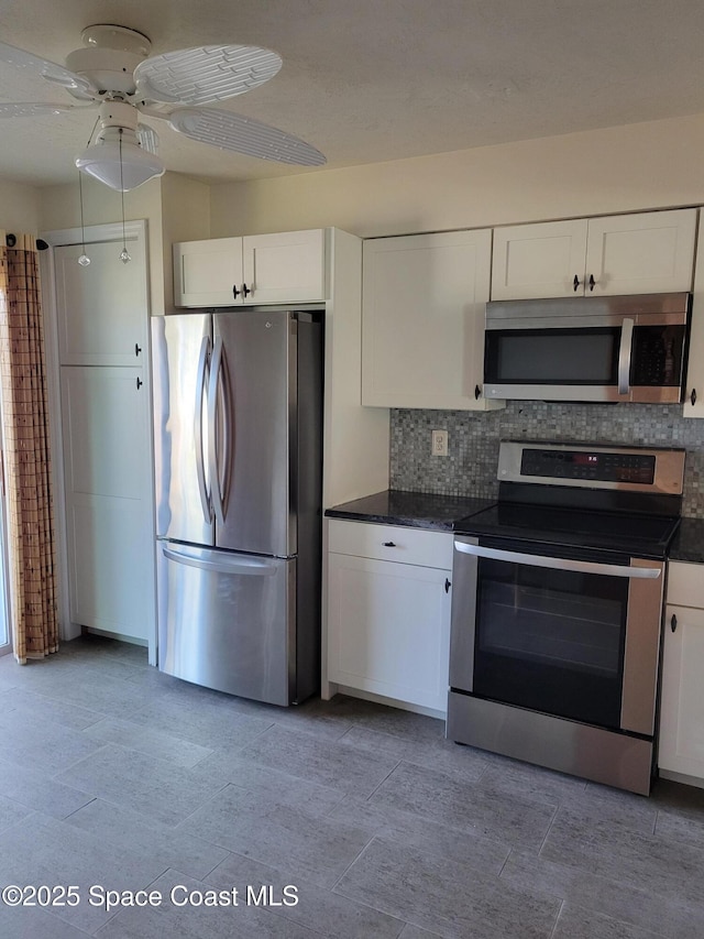 403 Hayes Ave, Cocoa Beach, FL 32931 - kitchen featuring stainless steel appliances, dark countertops, white cabinets, tasteful backsplash, and ceiling fan