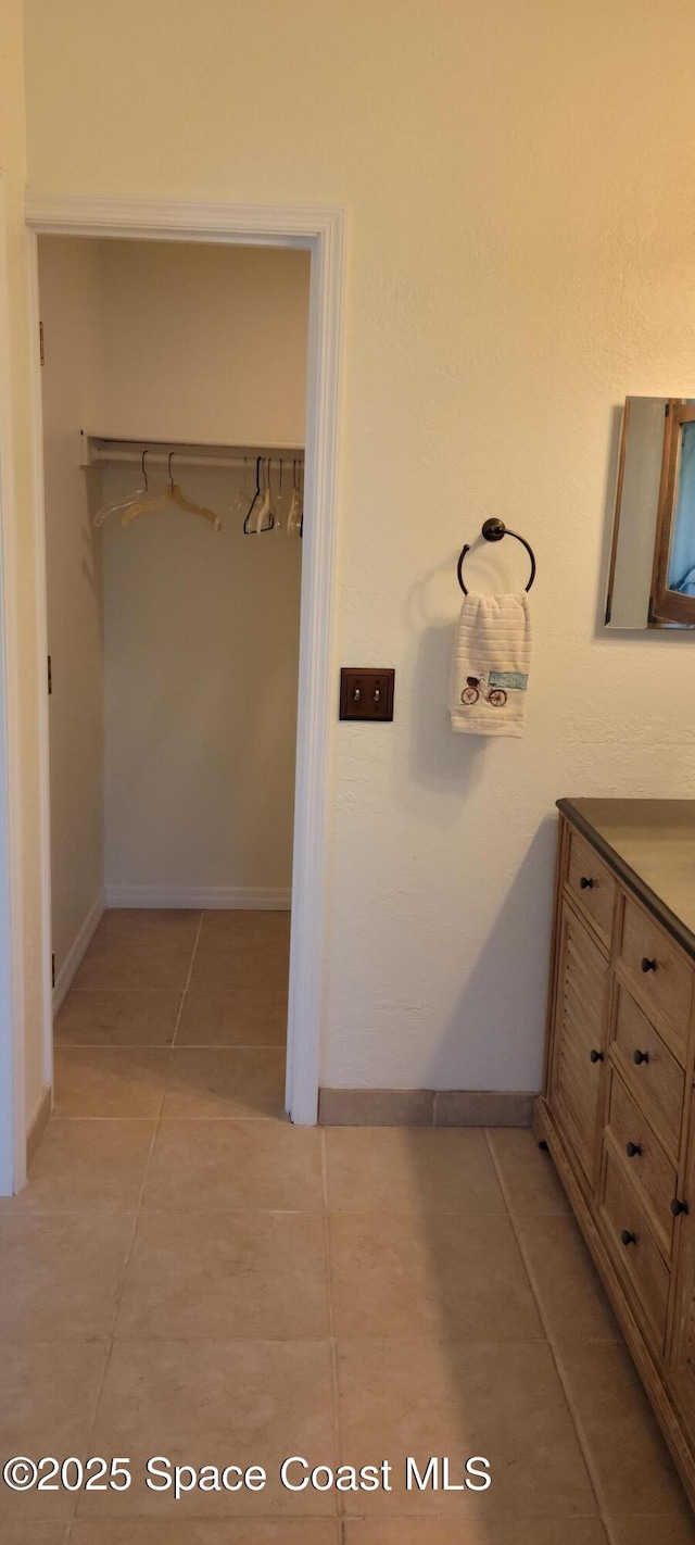 403 Hayes Ave, Cocoa Beach, FL 32931 - bathroom featuring vanity, tile patterned flooring, and a walk in closet